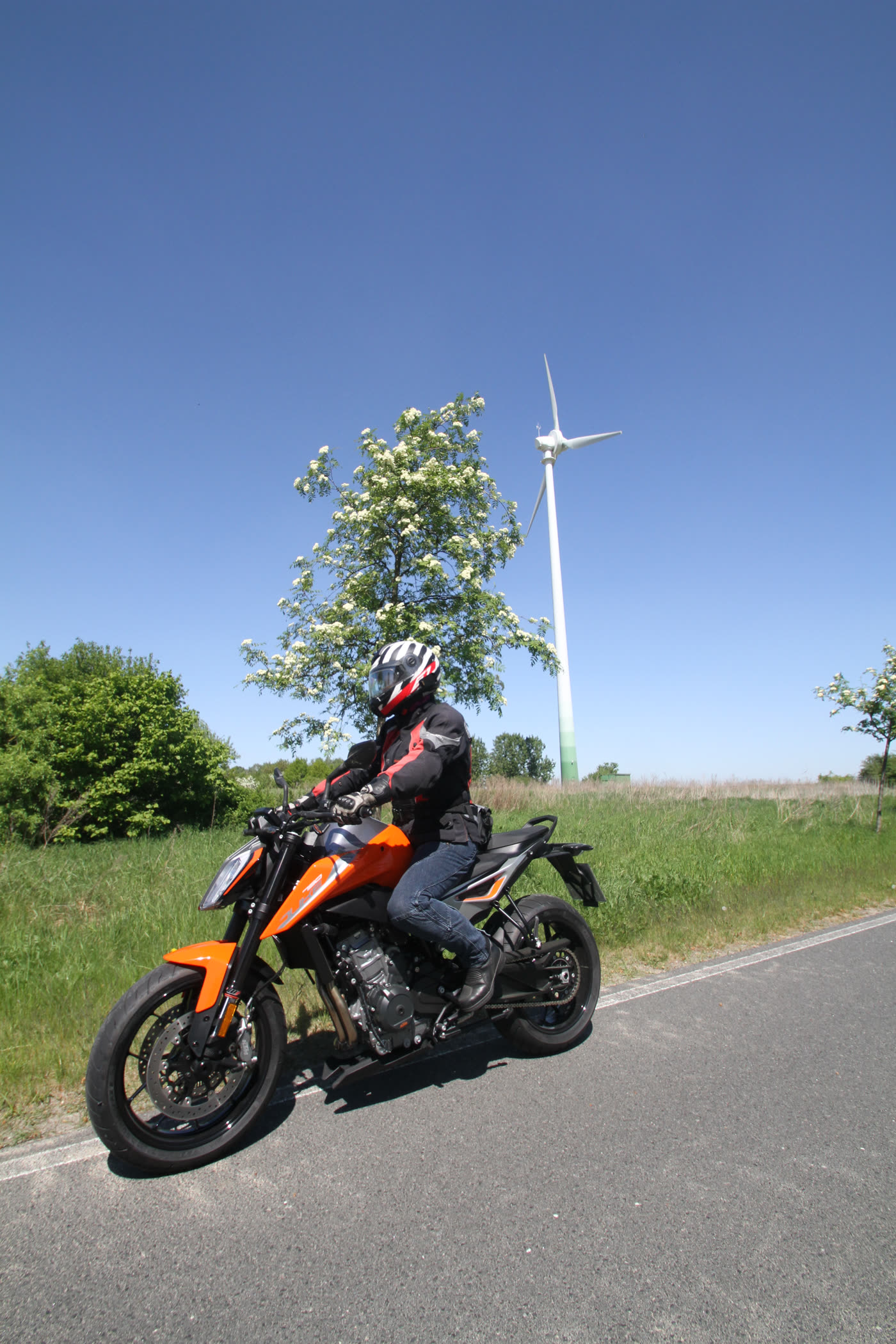 Motorrad auf einer Anhöhe, dahinter ein Windrad